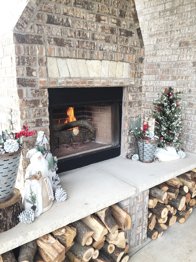Outdoor fireplace design idea with wood logs under neath hearth. Christmas Decoration ideas outside fireplace.